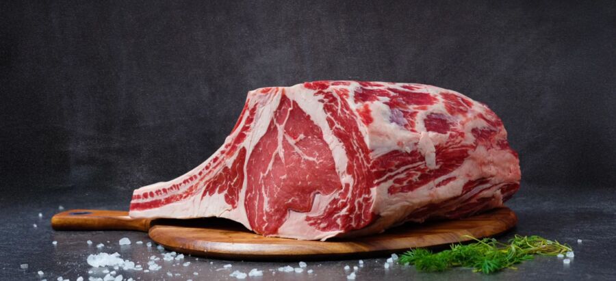 Carne de ribeye cruda de alta calidad sobre tabla de madera, perfecta para la cocina gourmet.