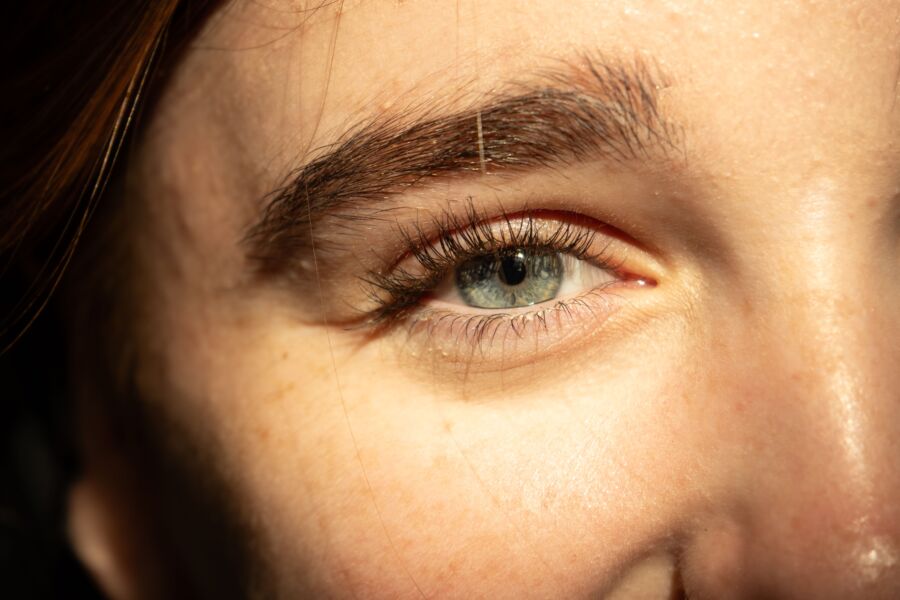Detallado primer plano de un ojo humano con iluminación natural destacando el iris y las pestañas.
