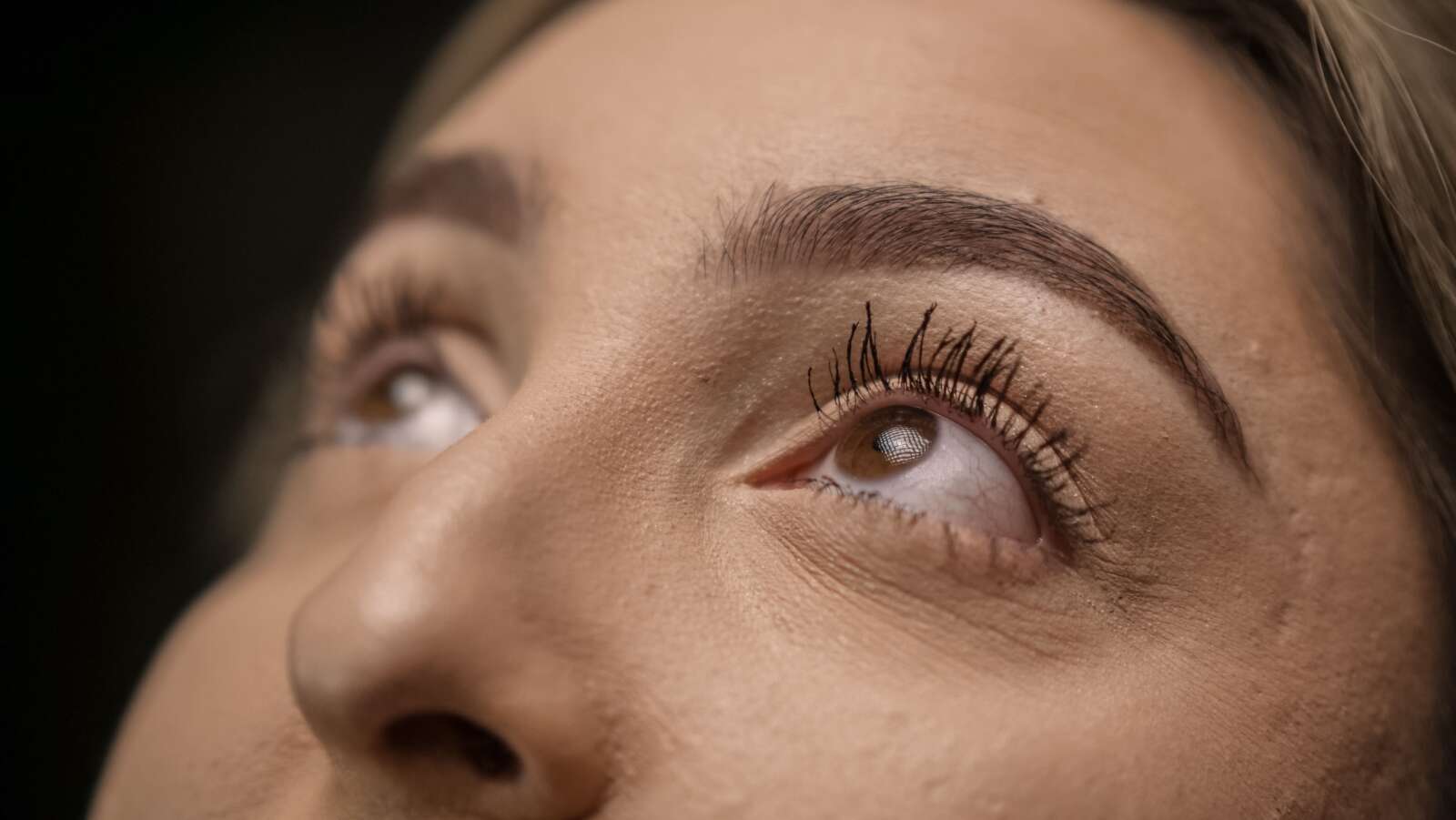 Primer plano detallado de los ojos femeninos mirando hacia arriba con pestañas largas y enfoque suave.
