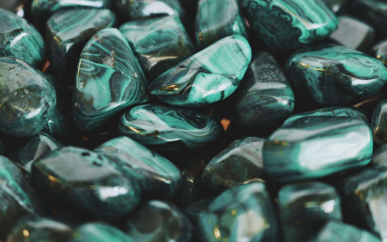 Primer plano de piedras de malaquita pulidas que muestran intrincados patrones y vibrantes tonos verdes.