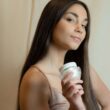 Hermosa mujer mostrando un producto para el cuidado de la piel en una pose elegante.