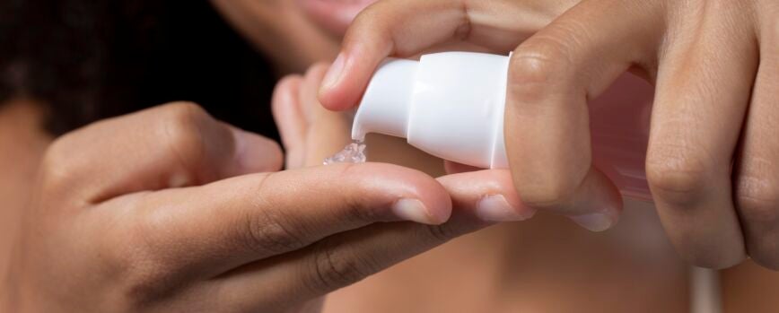 Bella modelo aplicando un tratamiento de crema cosmética en su cara en blanco