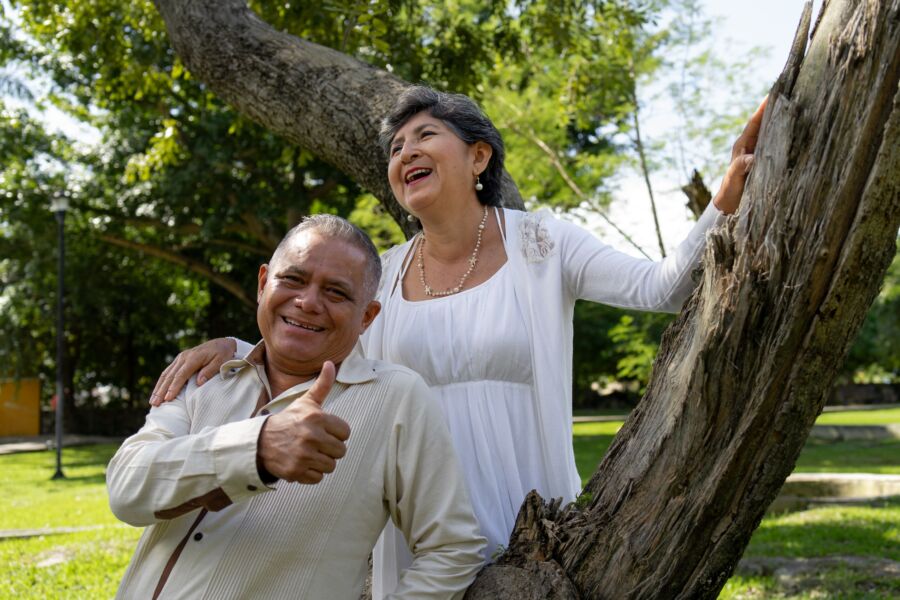 Pareja mayor feliz riendo y sonriendo en un parque soleado en Mérida, Yucatán, México.