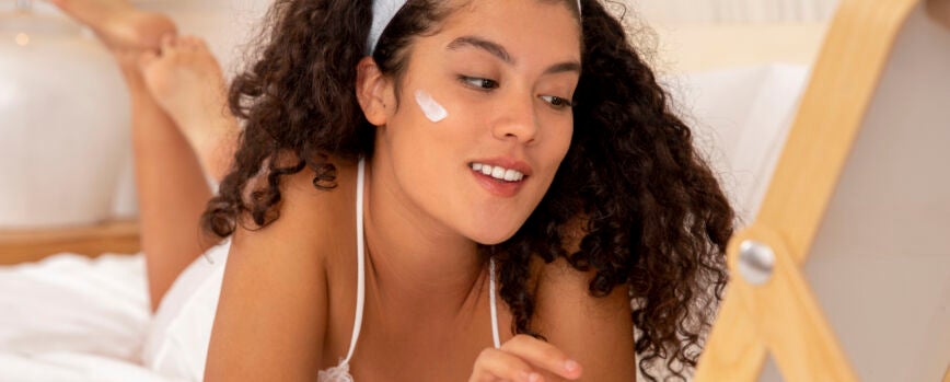 Mujer sonriente de tiro completo con crema facial