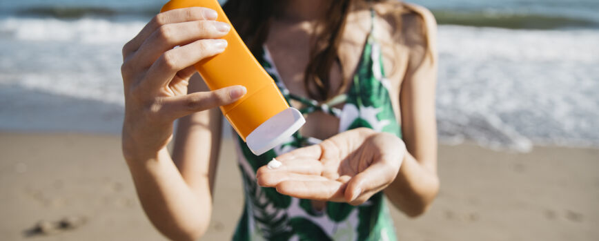 Mujer en la playa con crema solar