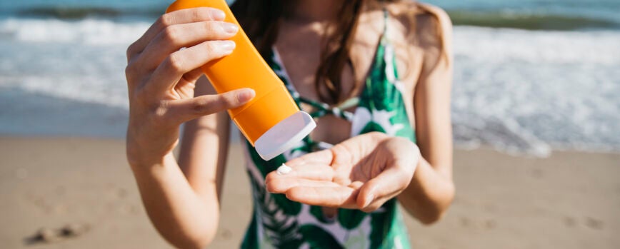 Mujer en la playa con crema solar