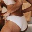 Recortar las bragas de ajuste de la mujer étnica anónima en el trasero con estrías en el baño
