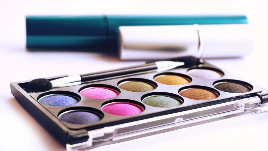 Primer plano de paleta de sombras de ojos de colores con pincel, ideal para temas de moda y belleza.