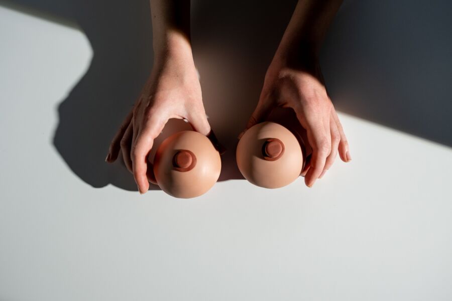 Representación artística de la conciencia de la salud de los senos usando manos con accesorios modelo bajo la luz.