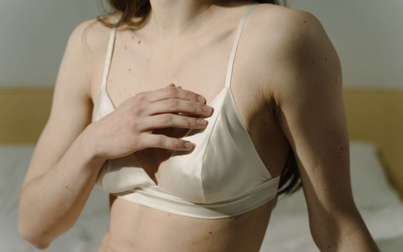 Primer plano íntimo de una mujer en lencería blanca en interiores con luz natural.