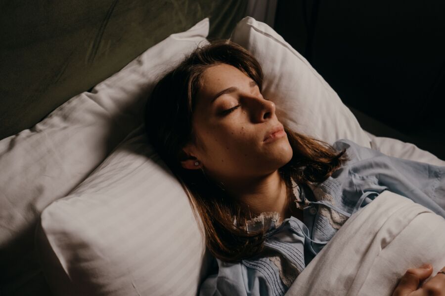 Mujer durmiendo tranquila en la cama, destacando la comodidad y la serenidad en un ambiente de dormitorio acogedor.