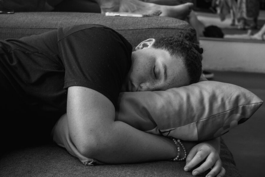 Una persona que duerme tranquilamente en un sofá, descansando su cabeza sobre una almohada en un entorno en blanco y negro.