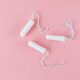 Imagen minimalista de tres tampones blancos sobre fondo rosa, ideal para temas de salud.