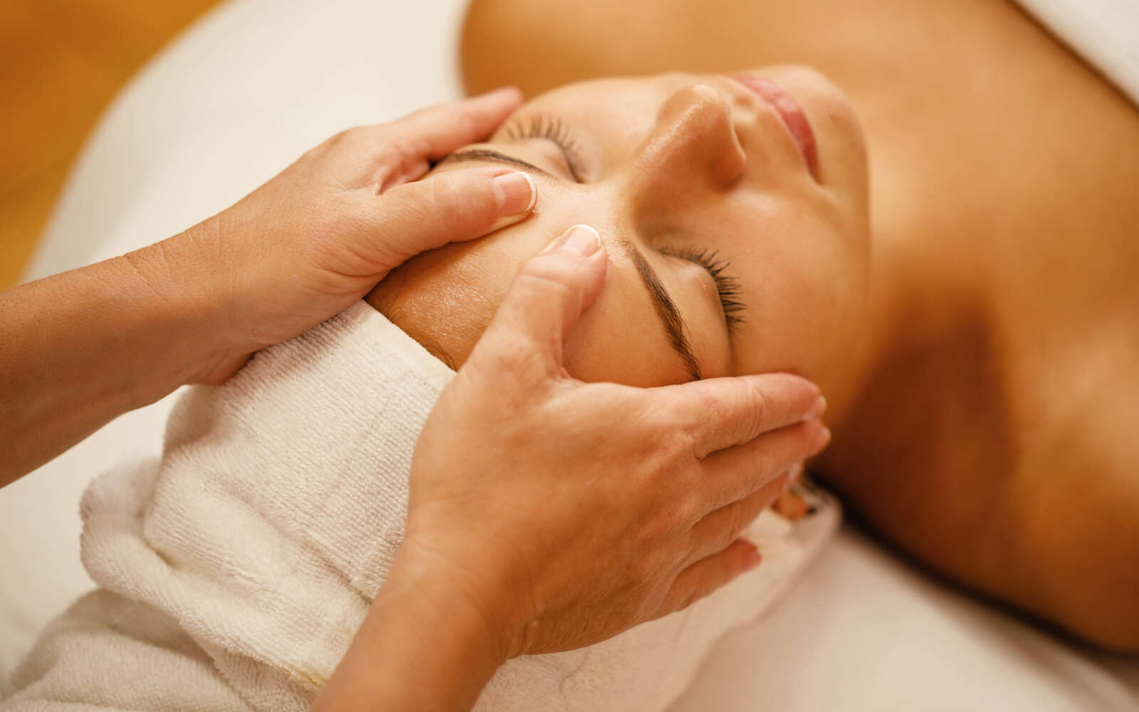El primer plano de una joven disfrutando de un masaje en la cabeza durante un tratamiento de belleza en el spa