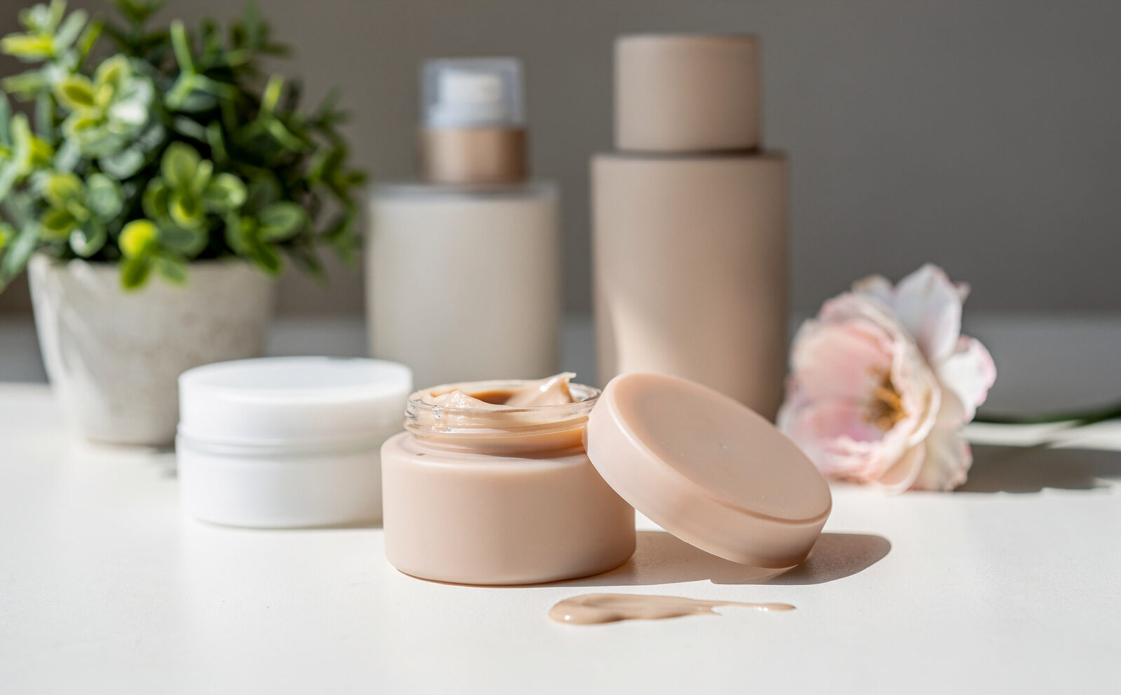 bodegón cosmética con plantita y flor al lado