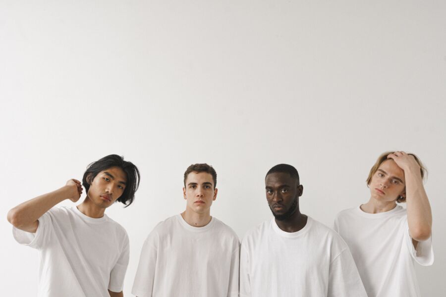 Cuatro jóvenes diversos posando en un estudio minimalista con fondo blanco.