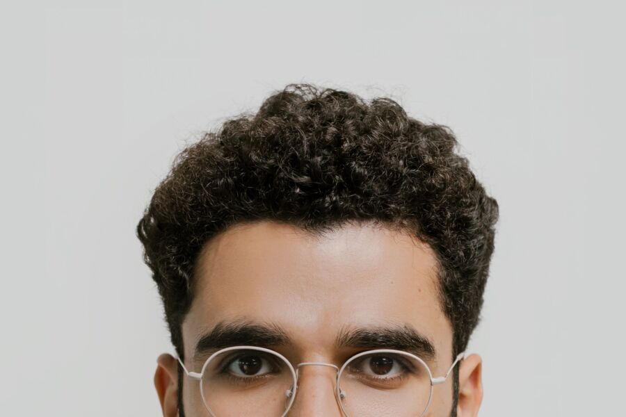 Detallado retrato en primer plano de un hombre con el pelo rizado y gafas.