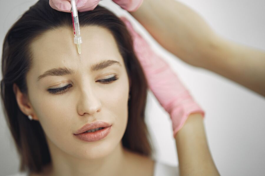 Primer plano del tratamiento facial con inyección en un entorno de spa, centrándose en la frente.