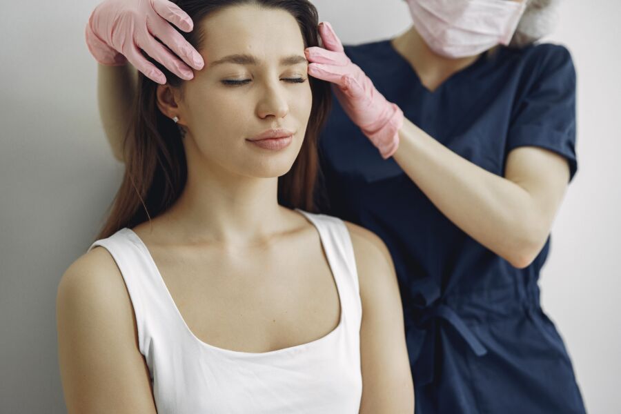 Mujer recibiendo un masaje calmante en la cabeza de un terapeuta en un entorno de spa.