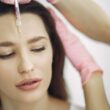 Primer plano del tratamiento facial con inyección en un entorno de spa, centrándose en la frente.
